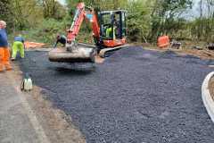 Excavator laying base course for site entrance